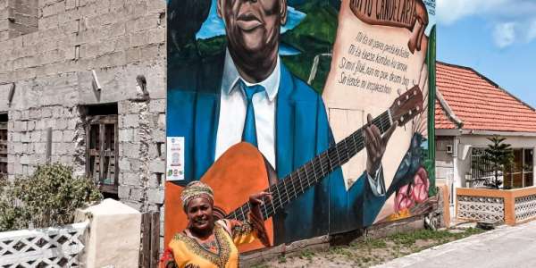 Gekleed in haar kenmerkende outfit, compleet met een dundu (traditionele Curacaoanse hoofddoek), neemt Jacqueline je graag mee op een van haar rondleidingen door Willemstad. 
